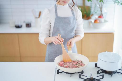 フライパンで挽き肉を痛めている女性の手元 フライパンで挽き肉を痛めている女性の手元の写真