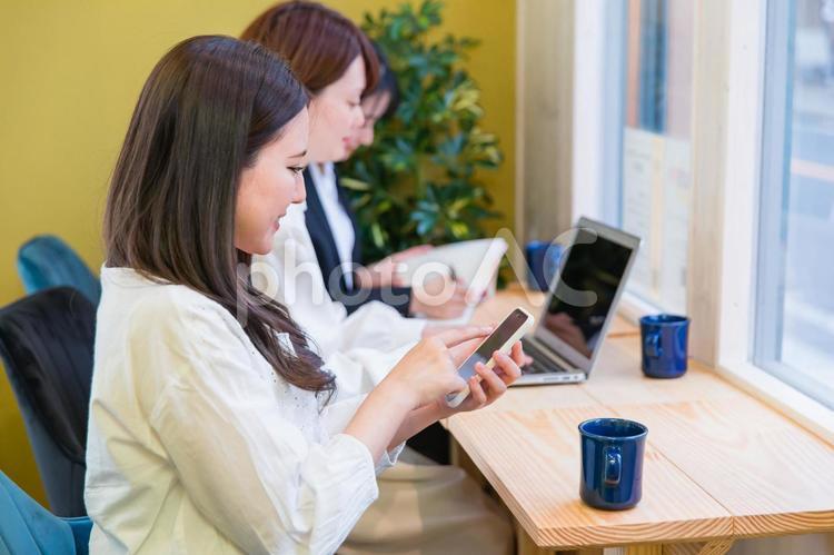 カフェの窓際カウンター席にいる女性（スマホを見る） スマートフォン,アプリ,スマホの写真素材
