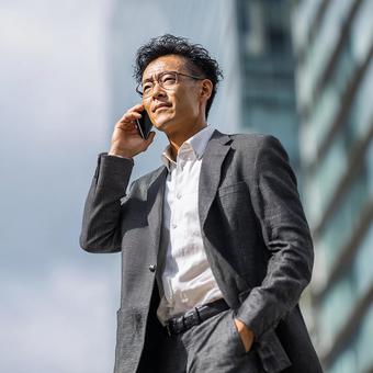 都会で電話する真剣な表情のビジネスマン 都会で電話する真剣な表情のビジネスマンの写真