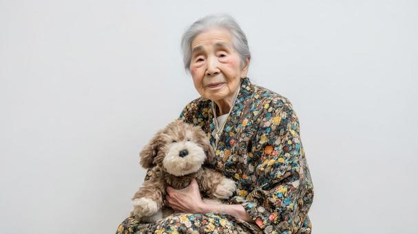 犬のぬいぐるみを大切そうに抱くおばあさん 犬のぬいぐるみを大切そうに抱くおばあさんの写真