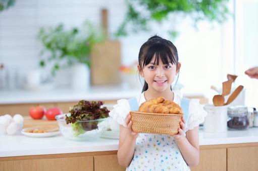 料理を楽しむエプロン姿の女の子のポートレート 女の子,クロワッサン,パンの写真素材