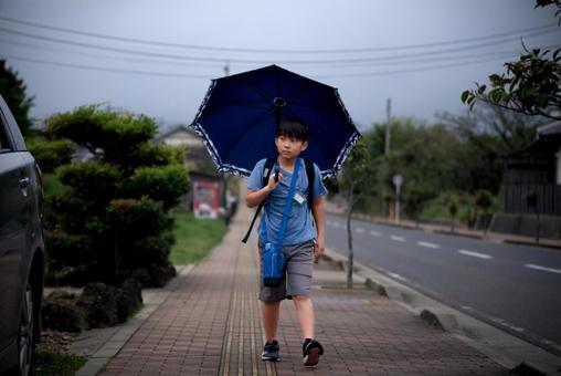<素材>雨の中雨傘をさして登校する少年 <素材>雨の中雨傘をさして登校する少年 子供,男性,人物の写真素材