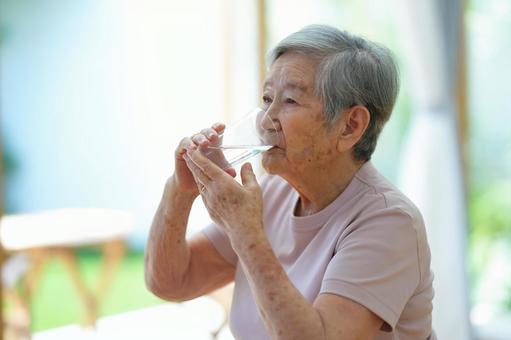 両手でコップを押さえて水を飲む女性 女性,水,飲むの写真素材