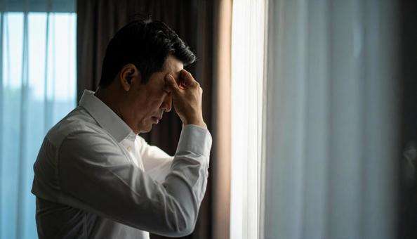 頭を抱えて落ち込む日本人男性 頭を抱えて落ち込む日本人男性の写真