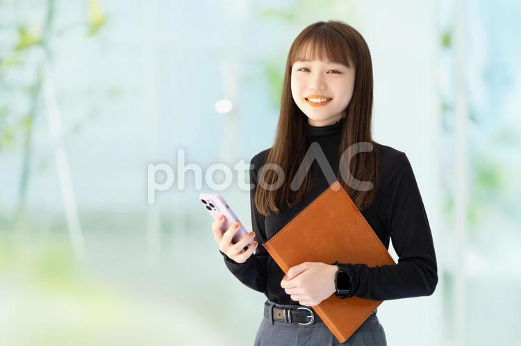 スマホとバインダーを持つ笑顔の女性 女性,スマホ,笑顔の写真素材