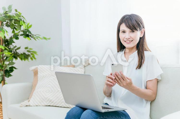 パソコンとスマホを使うミドル世代の女性 スマホ,テレワーク,スマートフォンの写真素材