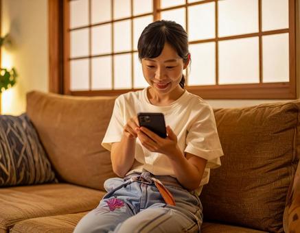 自宅でスマホを操作する女性 自宅でスマホを操作する女性の写真