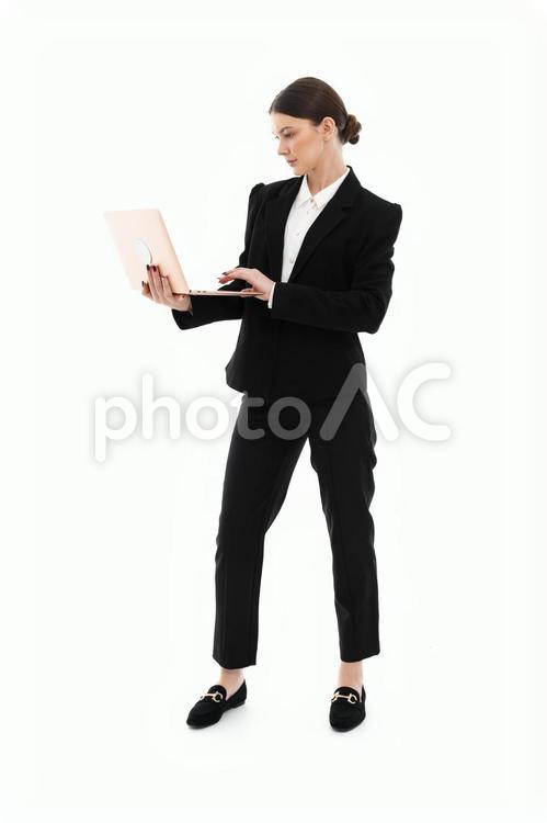 立ってパソコンを操作している女性 女性,ノートパソコン,持つの写真素材