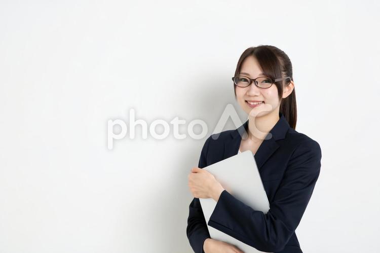パソコンを抱えているメガネのビジネスウーマン（コピースペース） 女,女性,日本人の写真素材