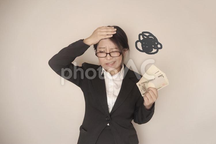 お金の束を持つスーツの女性 一万円,札束,悩みの写真素材