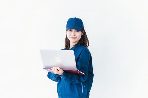作業服でパソコンを使う若い女性 作業服でパソコンを使う若い女性 ノートパソコン,コンピュータ,サポートの写真素材