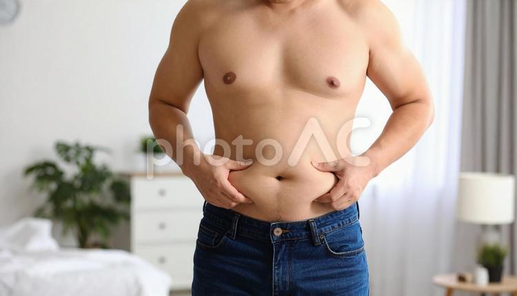 室内で自分のお腹の脂肪を気にする若い男性 人物,男性,ダイエットの写真素材