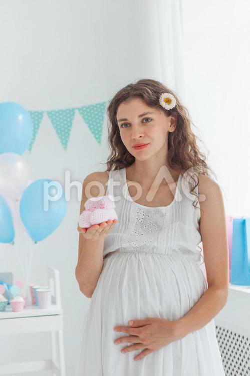 ベビーシューズを持って遠くを見る妊婦さん 女性,人物,風船の写真素材