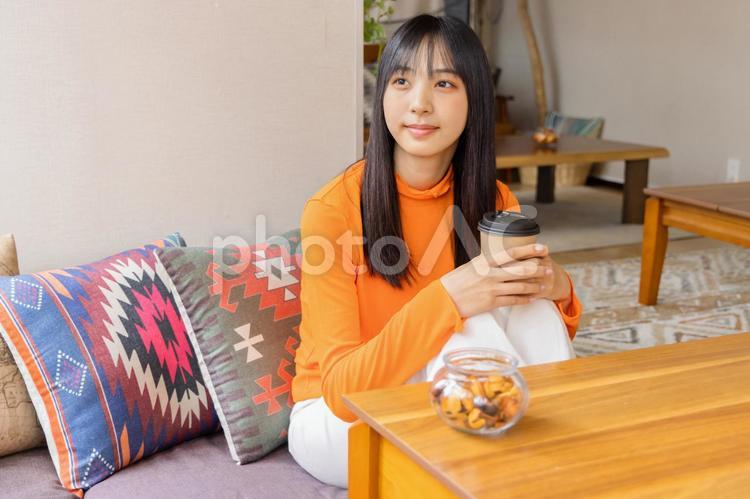 膝を立てコーヒー・紅茶を飲む若い女性 女性,ライフスタイル,日本人の写真素材