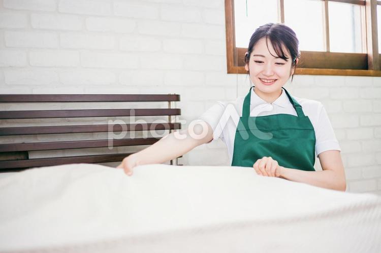 ベッドメイキングする家事代行の女性 ベッドメイキング,家事代行,客室清掃の写真素材