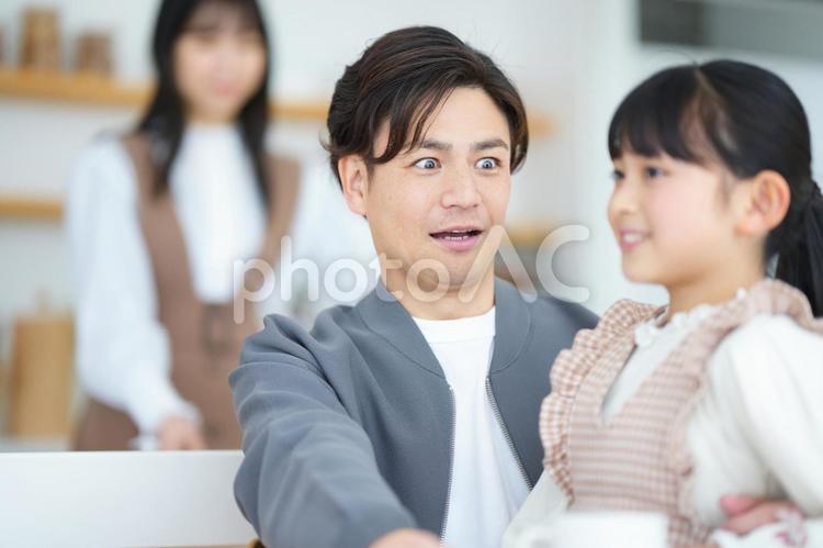 女の子を抱っこして驚く男性と後ろに女性 家族,女の子,女性の写真素材