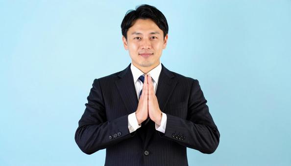両手をあわせてお願いしているビジネスマン 両手をあわせてお願いしているビジネスマンの写真