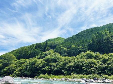 緑あふれる山の木々と穏やかな空模様 緑あふれる山の木々と穏やかな空模様の写真