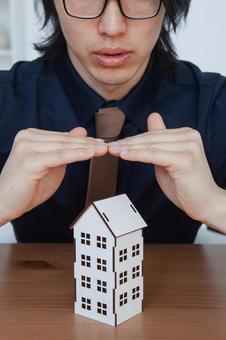 家の模型を使って説明する男性スタッフ 長髪,保険業,事務職の写真素材
