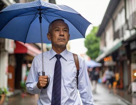 雨の商店街を歩くスーツ姿の男性 雨の商店街を歩くスーツ姿の男性の写真