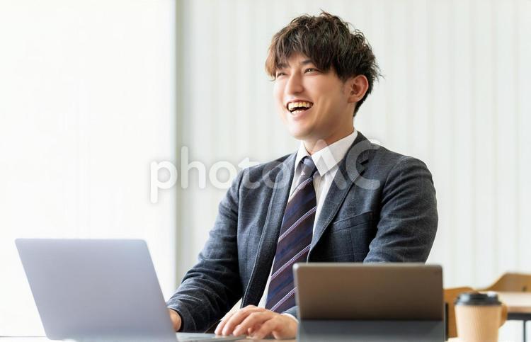 笑顔でパソコンを使う男性ビジネスマン 男性,ビジネス,ビジネスマンの写真素材