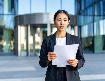 緊張した表情で書類を持つビジネスウーマンの写真