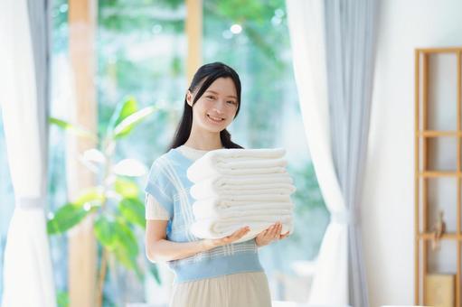 白い畳んだタオルを持ち笑う女性の写真