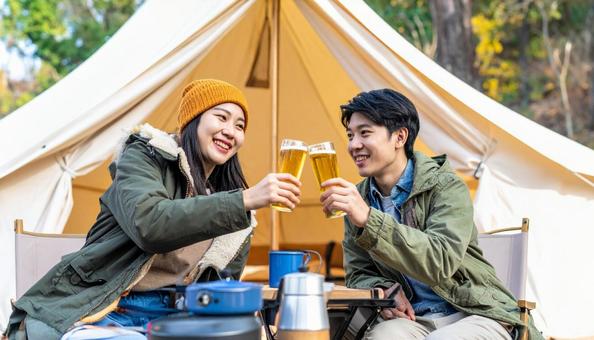 キャンプ場で乾杯しグルキャンを楽しむ男女の写真