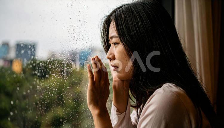 困った顔で窓の外を見る若い女性 困惑,頭痛,病気の写真素材