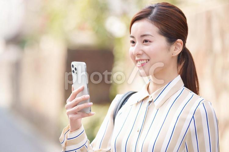 スマートフォンを持って遠くを見る女性 女性,スマートフォン,持つの写真素材