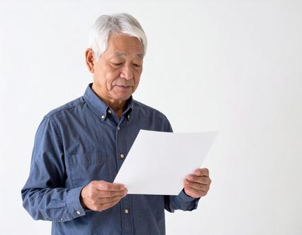 用紙を見る高齢男性 用紙を見る高齢男性の写真