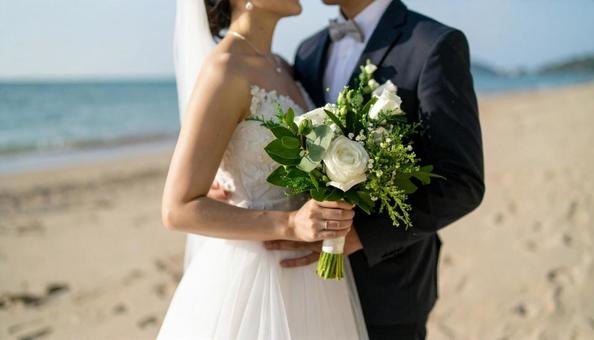 海辺でブーケを持ち顔を見合わせる新郎新婦 海辺でブーケを持ち顔を見合わせる新郎新婦の写真