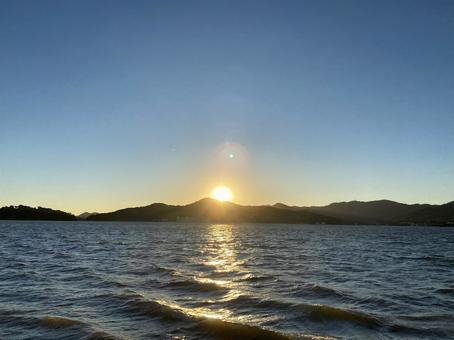 風が強く吹く湖の対岸の山に夕陽が沈む 湖,雲,初夏の写真素材