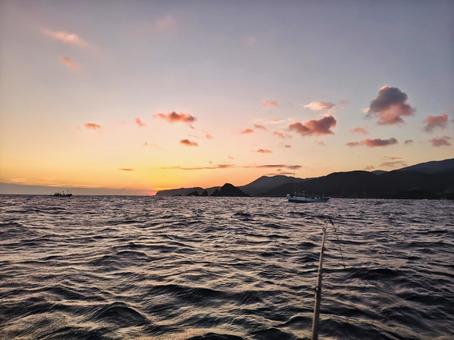 The sunset-colored sea and the silhouette of a fishing rod, JPG