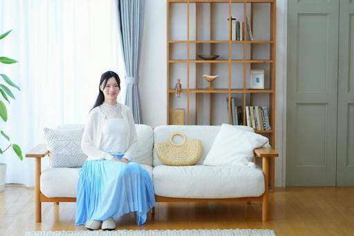ソファに座る青いスカートの女性の写真