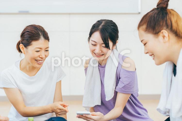スポーツジムでスマホを見て談笑する女性たち スポーツジム,スマホ,体験レッスンの写真素材
