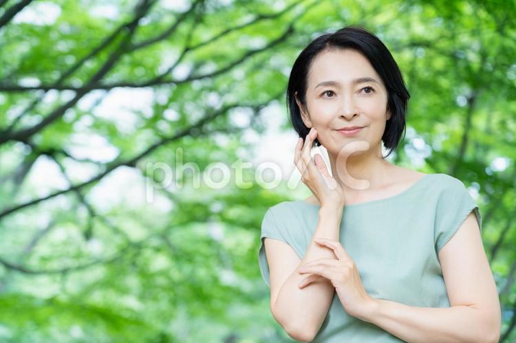 新緑の中でスキンケアをするミドルの女性 ビューティー,スキンケア,女性の写真素材