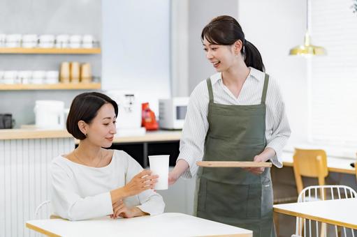 接客をするエプロンをつけた女性 接客をするエプロンをつけた女性 カフェ,店員,笑顔の写真素材
