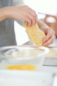 パン粉を付けたとんかつを持つ手 パン粉を付けたとんかつを持つ手の写真