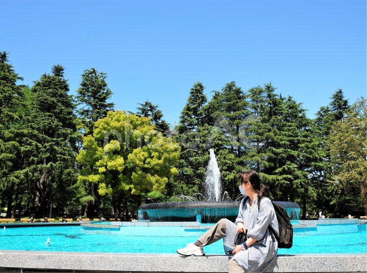 日比谷公園の噴水広場で癒されるマスク姿の女性 噴水,快晴,屋外の写真素材