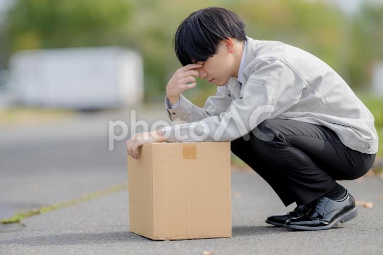 疲れてそうな作業服男性とトラック 男性,作業服,段ボールの写真素材