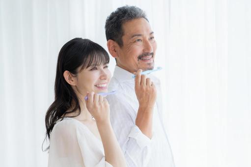 白バックで歯磨きをするミドルの夫婦 白バックで歯磨きをするミドルの夫婦 歯磨き,家族,ホワイトニングの写真素材