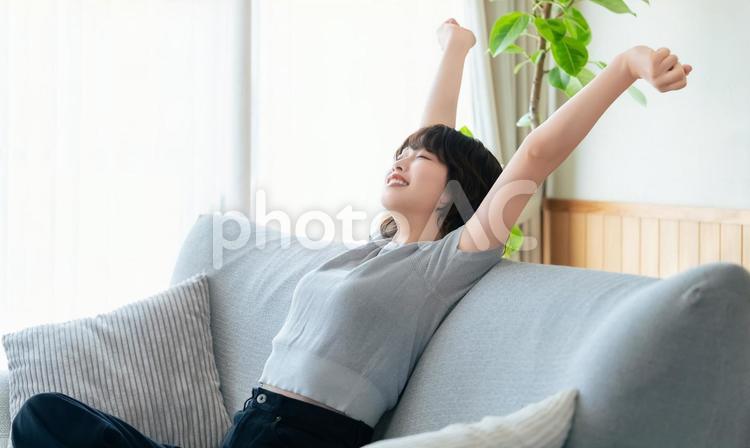 腕を伸ばしてリラックスする女性 女性,ソファ,微笑むの写真素材