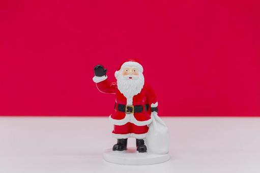 真っ赤な背景に手を振るサンタクロース人形 サンタクロース,クリスマス,プレゼントの写真素材