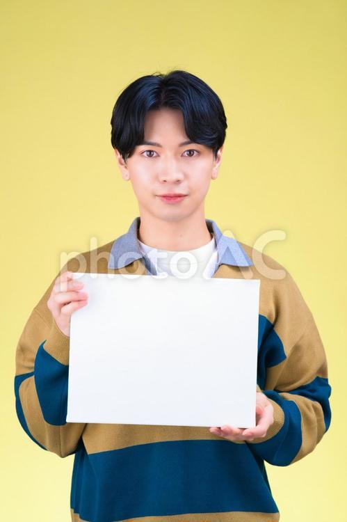 カメラ目線でボードを持つセンターパートの男性 男性,メッセージボード,持つの写真素材