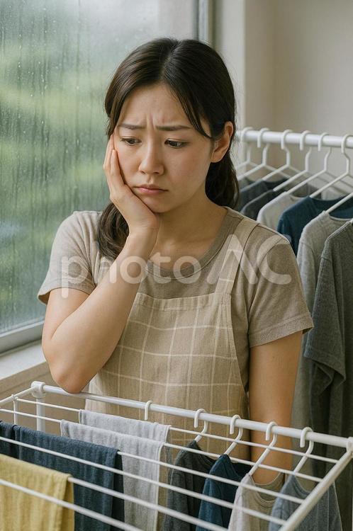 雨で洗濯物が乾かなくて困っている女性 梅雨,雨,洗濯物の写真素材
