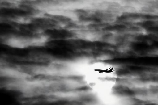 太陽と雲を横切る飛行機_モノクロ 飛行機,空,シルエットの写真素材