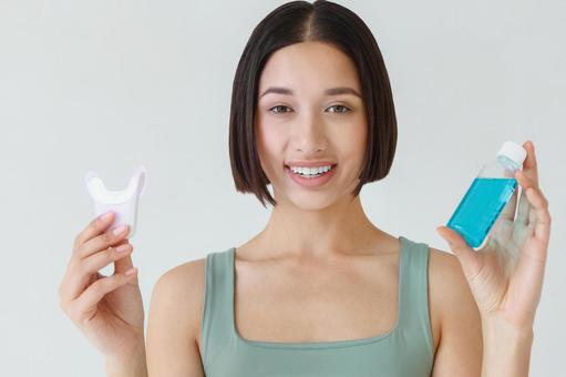マウスウォッシュとセルフホワイトニングを持っている女性 マウスウォッシュとセルフホワイトニングを持っている女性の写真