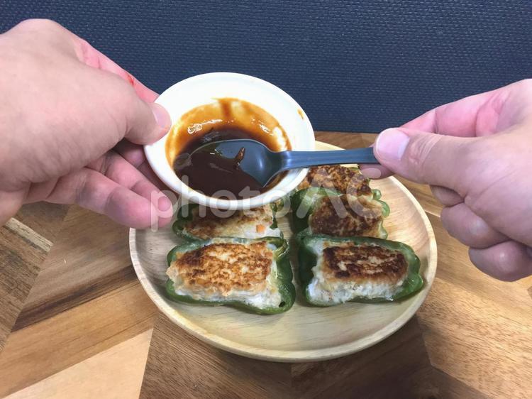 ピーマンの肉詰めにソースをかける ピーマン,肉詰め,ソースの写真素材