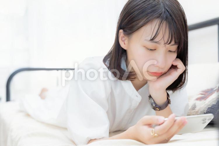 スマホ動画を見る頬杖ついた女性 女性,スマホ,スマートフォンの写真素材